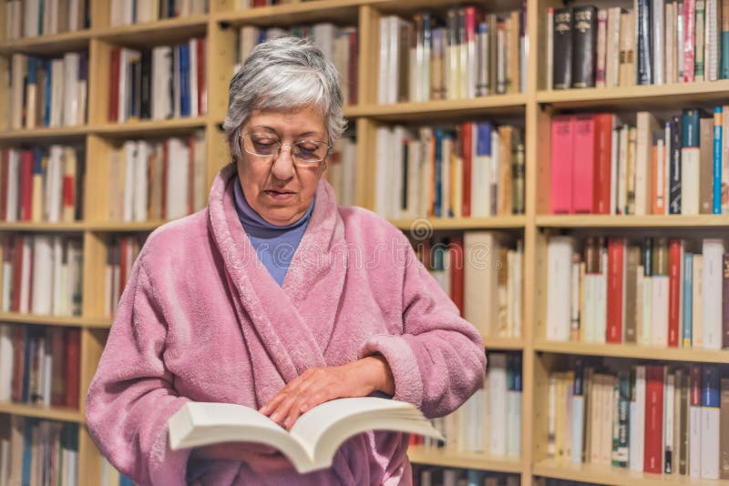 Senior Woman Reading a Book at Home. Concentrated Expression Stock