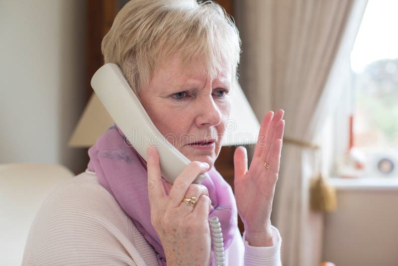 Senior Woman Receiving Unwanted Telephone Call At Home stock image Senior Woman Receiving Unwanted Telephone Call At Home stock image