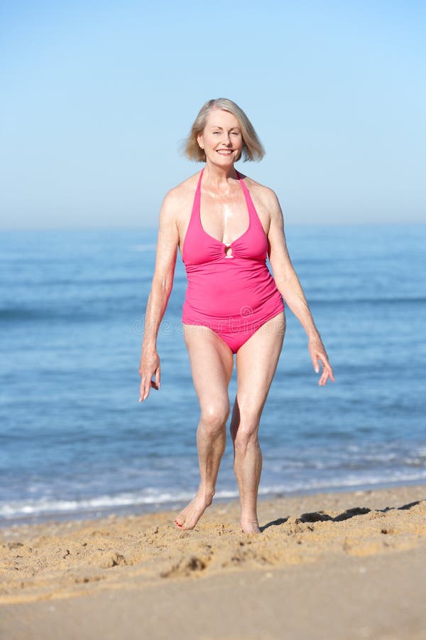 Senior Woman Running Along Summer Beach.