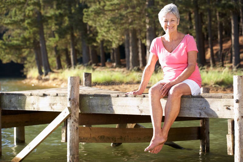 Senior woman sitting by lake. 