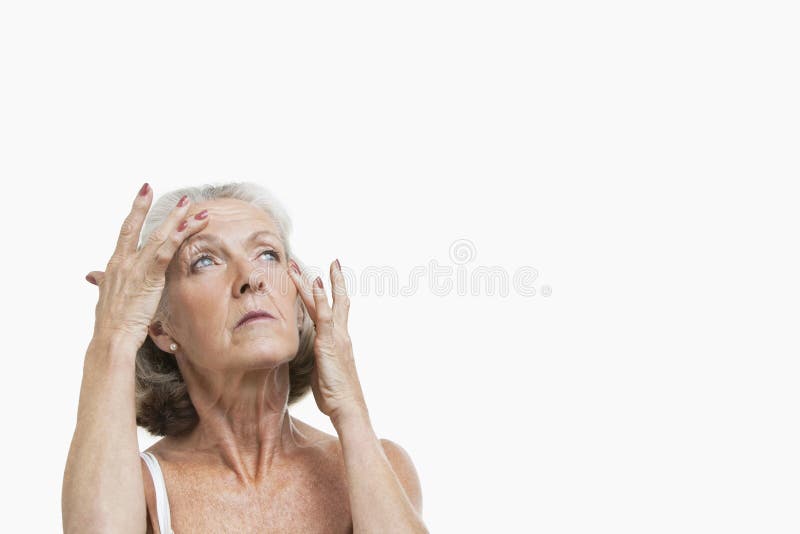 Senior woman suffering from headache against white background