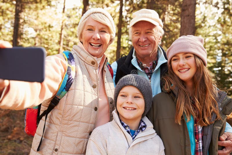 Senior woman taking outdoor selfie with grandkids and spouse