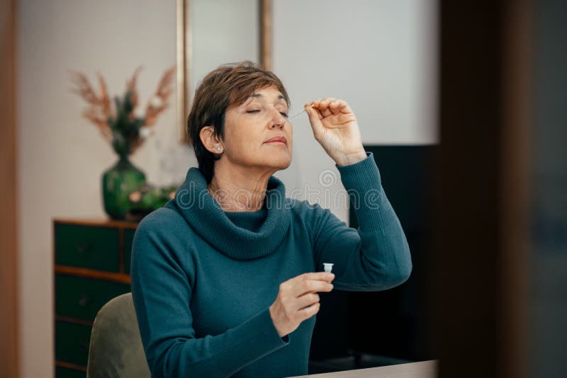 Senior woman using an nasal swab for covid 19 detection, self testing royalty free stock image