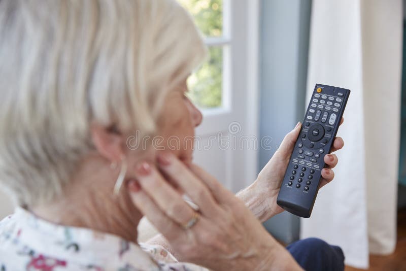 Senior Woman Using TV Remote Control, Over Shoulder View Stock Image