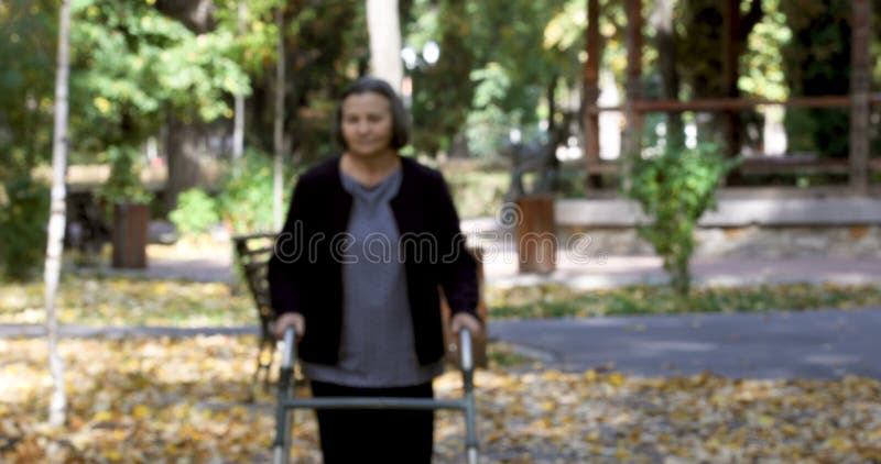 Senior woman walking with walker in autumn park