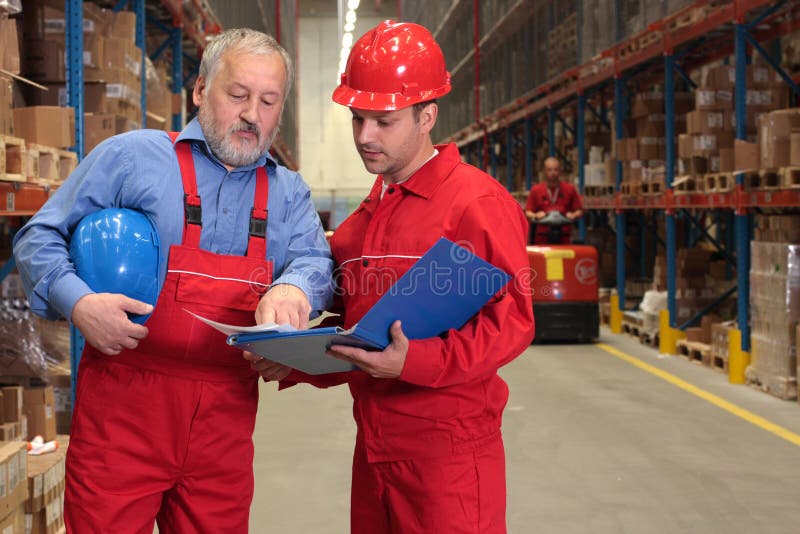 Two workers in uniforms in warehouse. one is older, one is younger, different activities. Architect uniform stock images, royalty-free photos and pictures
