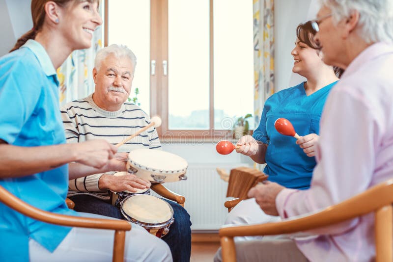 Senioren in de verpleegkunde die muziek maken met ritme-instrumenten