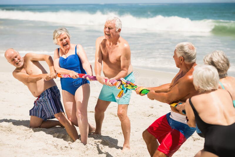 Seniors playing tug of war at the beach on a sunny day