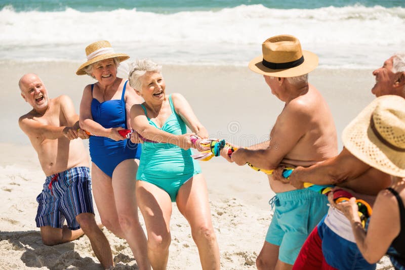 Seniors playing tug of war at the beach on a sunny day