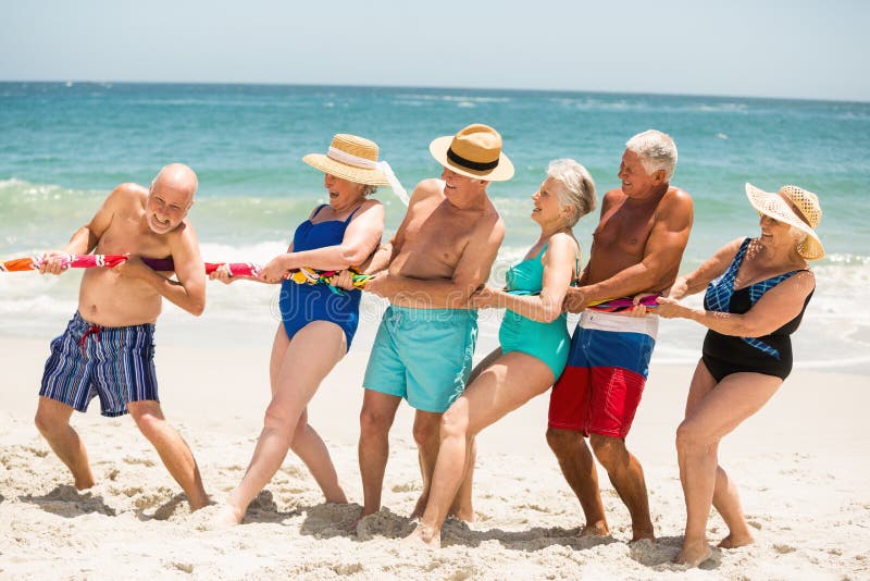 Seniors playing tug of war at the beach on a sunny day