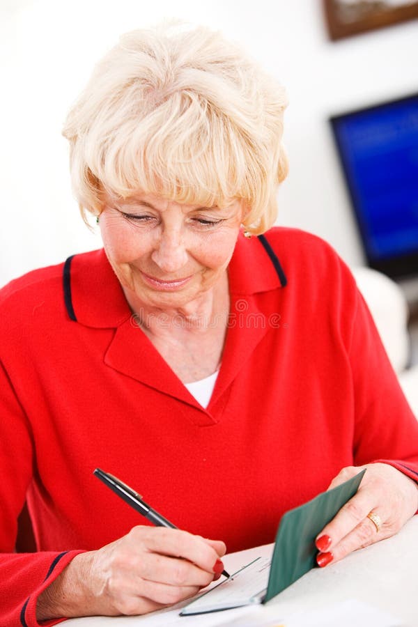 Seniors: Woman Cheerfully Writing Checks royalty free stock image Seniors: Woman Cheerfully Writing Checks royalty free stock image