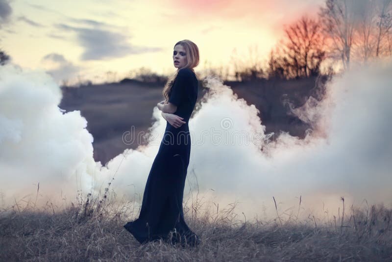 Sensual beautiful girl in smoke on nature royalty free stock photography