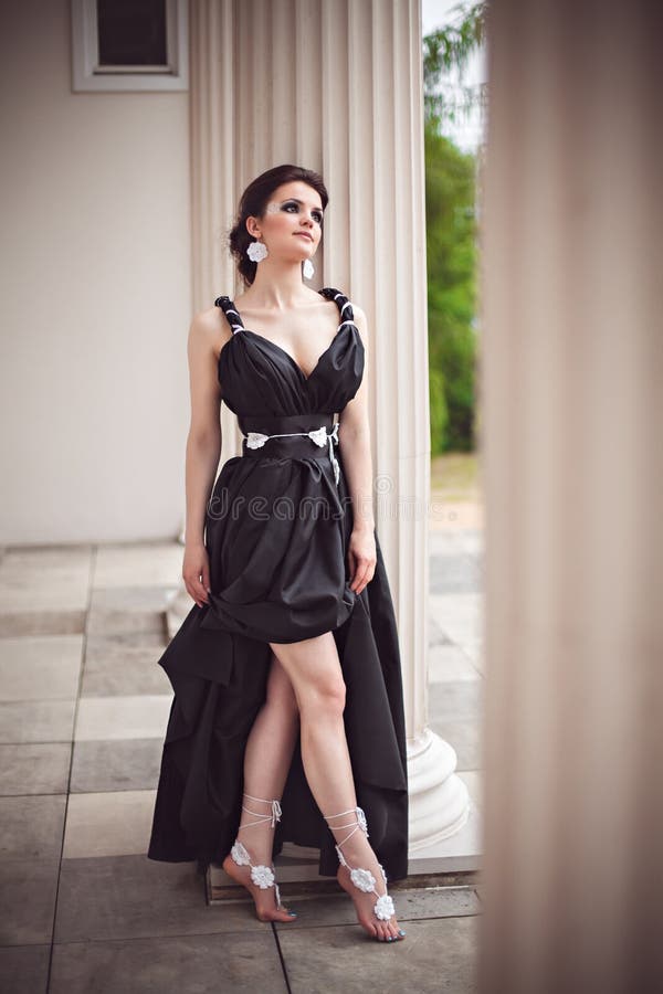 Sensual girl in long black dress at column