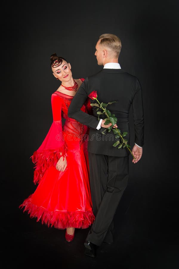 Sensuele vrouw en man dans met roze bloem Vrouw in rode kleding en macho in smoking Paar van balzaaldansers in liefde valentin royalty-vrije stock foto's Sensuele vrouw en man dans met roze bloem Vrouw in rode kleding en macho in smoking Paar van balzaaldansers in liefde valentin royalty-vrije stock foto's