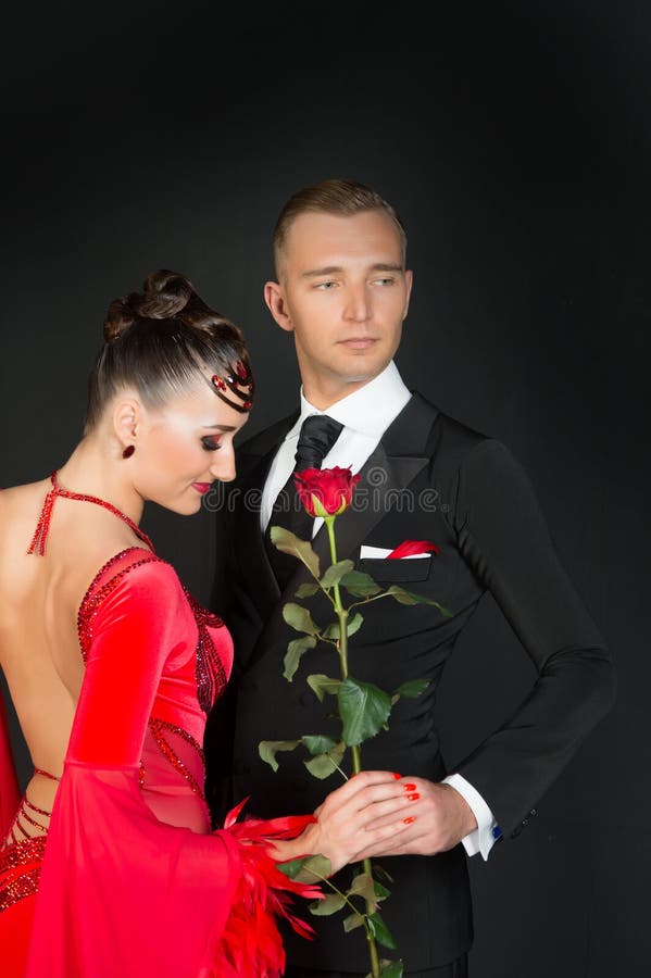 Sensuele vrouw en man met roze bloem Vrouw in rode kleding en macho in smoking Paar van balzaaldansers in liefde Rood nam toe royalty-vrije stock afbeelding Sensuele vrouw en man met roze bloem Vrouw in rode kleding en macho in smoking Paar van balzaaldansers in liefde Rood nam toe royalty-vrije stock afbeelding