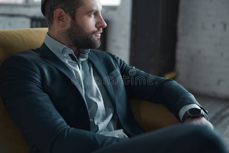 Sentimento confortável em seu estilo Opinião superior o homem novo considerável no terno completo que olha ausente ao sentar-se n fotos de stock royalty free Sentimento confortável em seu estilo Opinião superior o homem novo considerável no terno completo que olha ausente ao sentar-se n fotos de stock royalty free