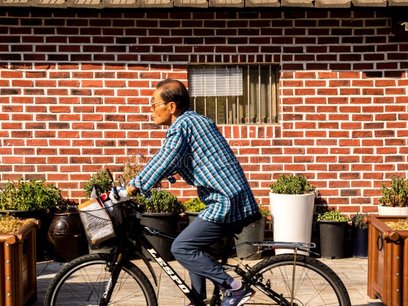Seoul, Corea del Sud - 14 giugno 2017: Uomo anziano che guida una bici sulla via di Seoul fotografia stock libera da diritti Seoul, Corea del Sud - 14 giugno 2017: Uomo anziano che guida una bici sulla via di Seoul fotografia stock libera da diritti