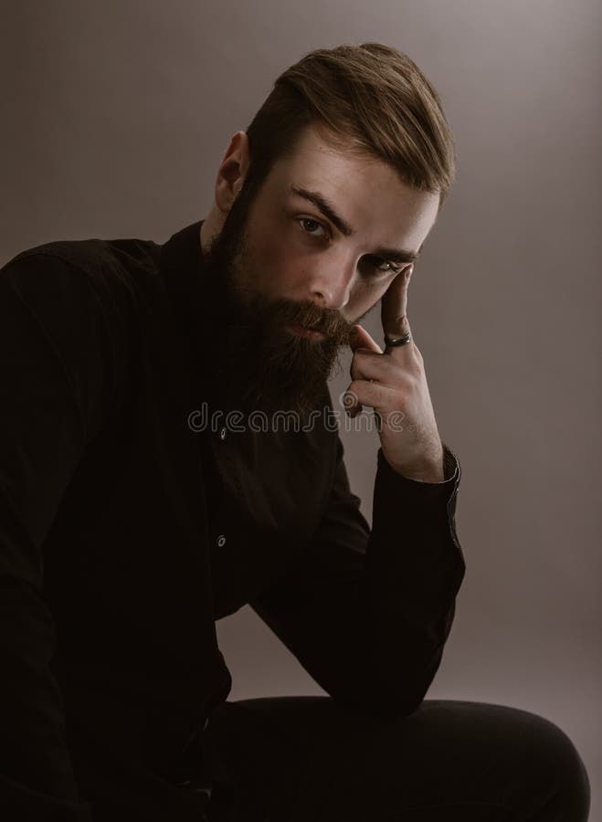 Sepia het fotoportret van een peinzende mens met een baard kleedde zich in het zwarte overhemd op de witte achtergrond stock afbeelding Sepia het fotoportret van een peinzende mens met een baard kleedde zich in het zwarte overhemd op de witte achtergrond stock afbeelding