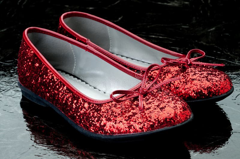 Sequined red slippers on dark tile.