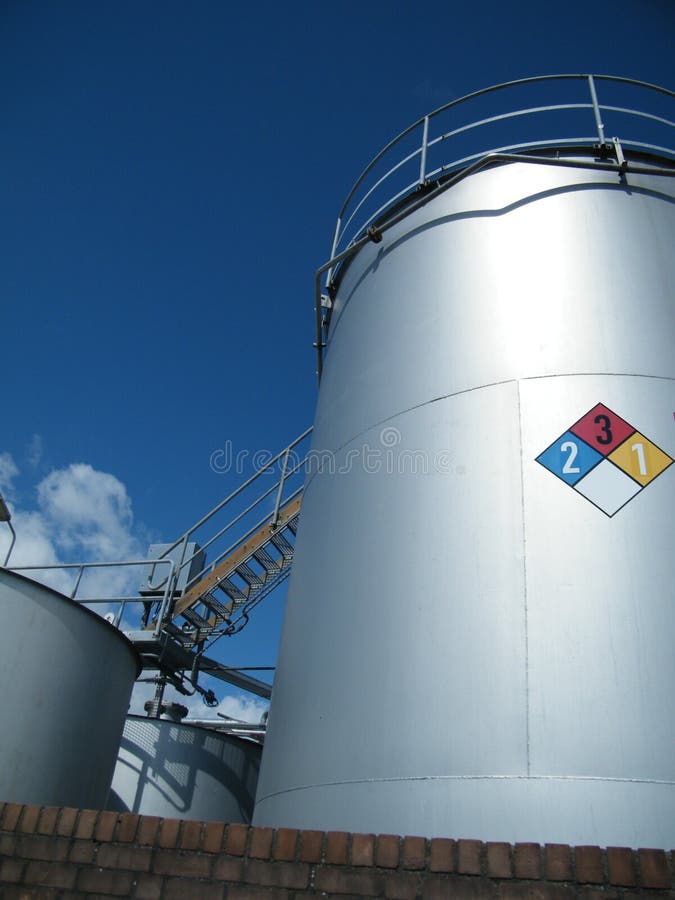 Serbatoi industriali per i prodotti chimici con la segnaletica di sicurezza immagini stock Serbatoi industriali per i prodotti chimici con la segnaletica di sicurezza immagini stock