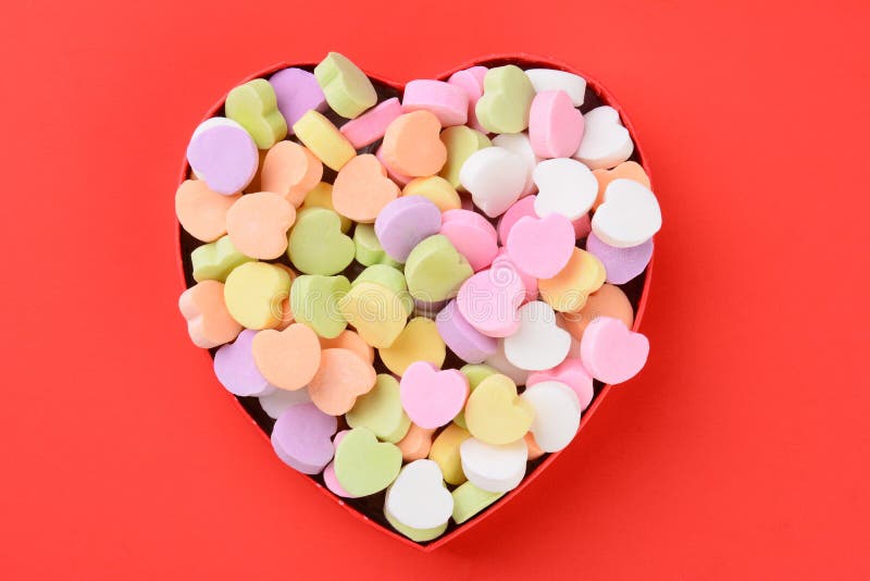 High angle view of a heart shaped box filled with Valentine's Day Candies. The box in the middle of a red background. The heart shaped candy is bland and ready for your message. High angle view of a heart shaped box filled with Valentine's Day Candies. The box in the middle of a red background. The heart shaped candy is bland and ready for your message.