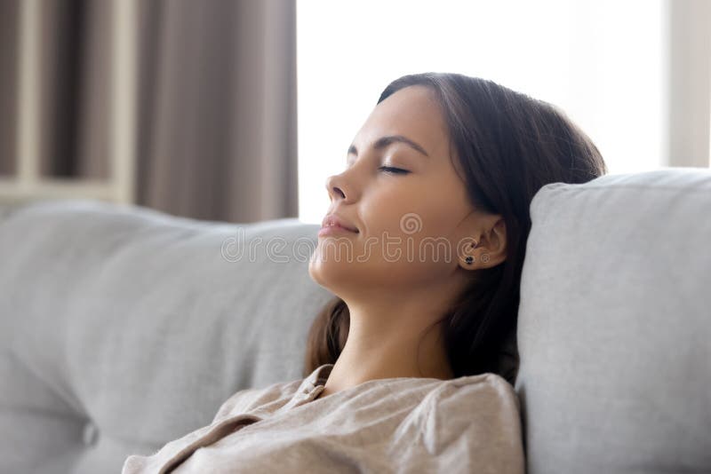 Serene calm woman relaxing leaning on comfortable couch having nap