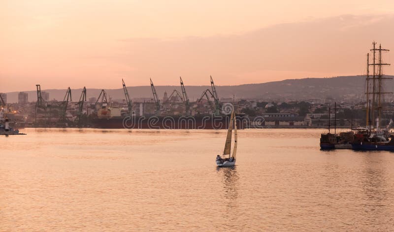 Serene evening view featuring a single sailboat cruising on tranquil waters stock images