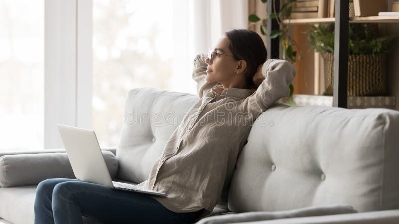 Serene woman with computer on laps leaning on couch resting royalty free stock photography Serene woman with computer on laps leaning on couch resting royalty free stock photography