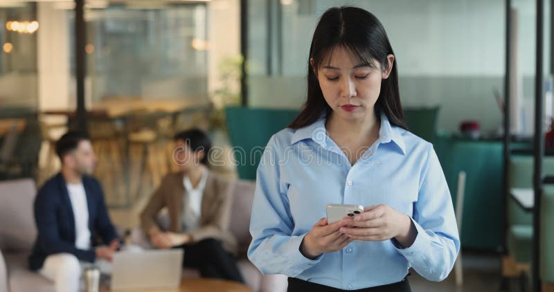 Seria giovane impiegata di un'azienda asiatica che scrive per telefono cellulare archivi video