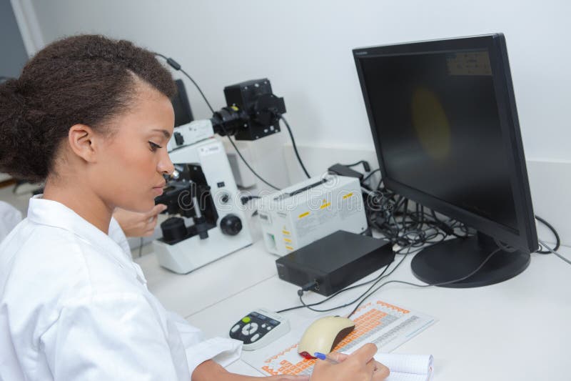 Seria scienziata che scrive negli appunti in laboratorio immagini stock libere da diritti