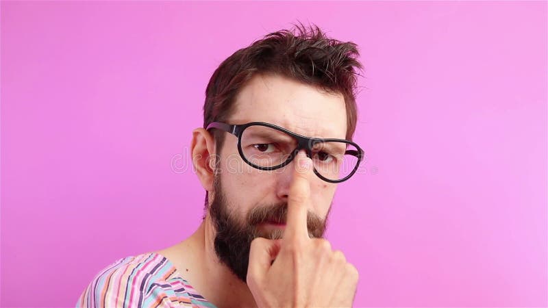 Serieus bebaard man in een bril kijkt naar de camera op roze achtergrond