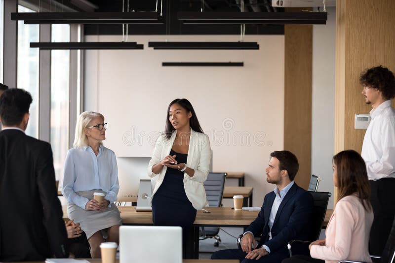 Serious asian coach speaking at diverse corporate group meeting