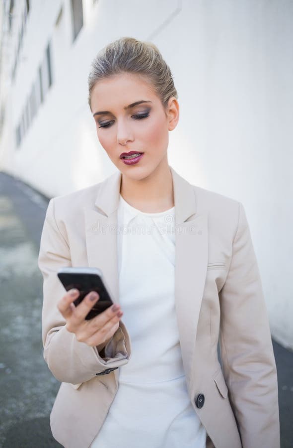 Serious attractive businesswoman sending a text