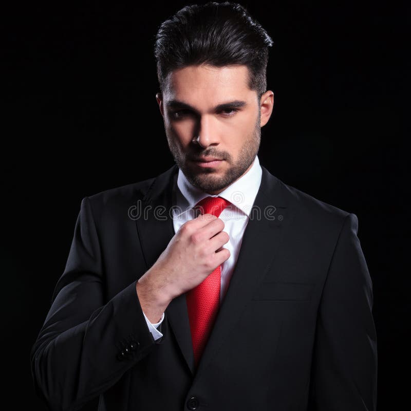 Serious business man adjusts his tie stock images