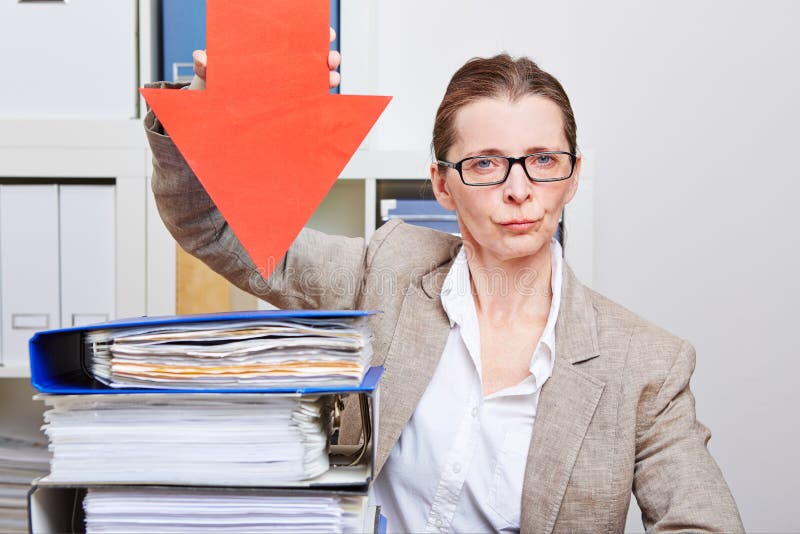 Serious business woman in her office pointing with arrow to many files. Serious business woman in her office pointing with arrow to many files