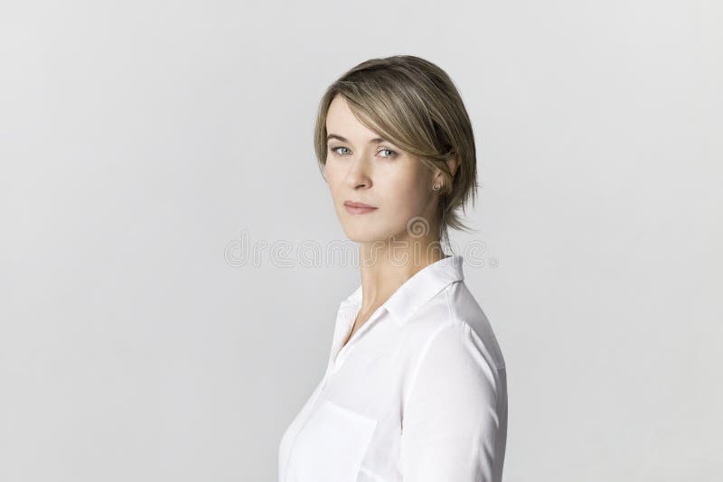 Serious businesswoman in white shirt portrait against white wall stock image Serious businesswoman in white shirt portrait against white wall stock image