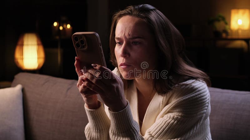 Serious Caucasian Woman Chats On The Internet Using Phone At Evening Home