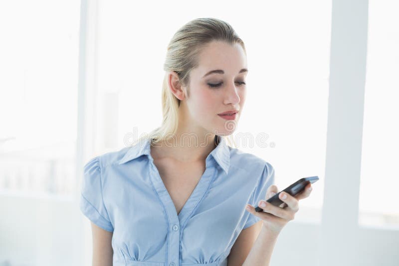 Serious classy businesswoman messaging with her smartphone royalty free stock image Serious classy businesswoman messaging with her smartphone royalty free stock image
