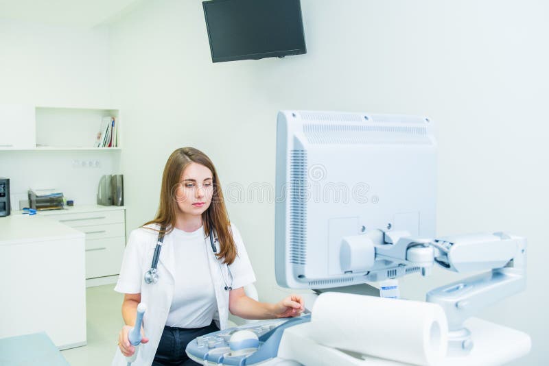 Serious, concentrated young doctor, specialist using Ultrasound Scanning Machine for pacient testing. Copy space. Selective focus royalty free stock photo