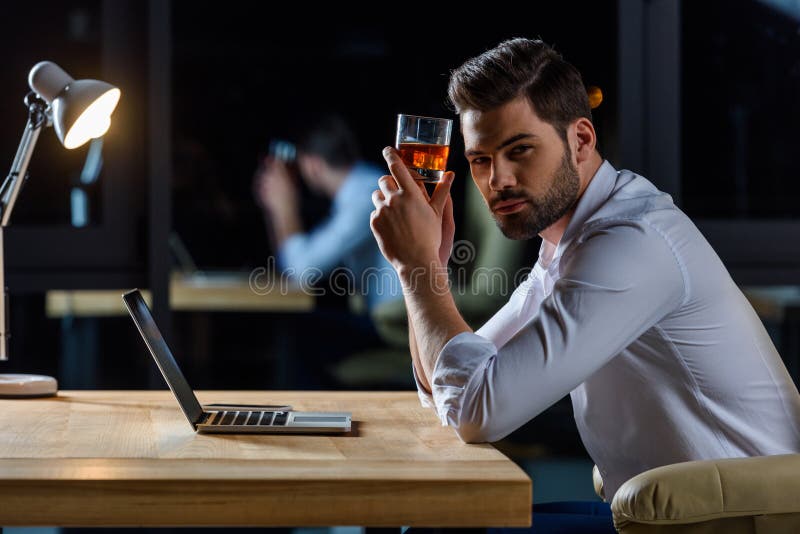 serious handsome businessman sitting at table and holding glass royalty free stock photos serious handsome businessman sitting at table and holding glass royalty free stock photos