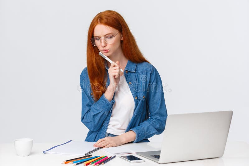 Serious looking focused and determined redhead female working over important project, design for company, work freelance