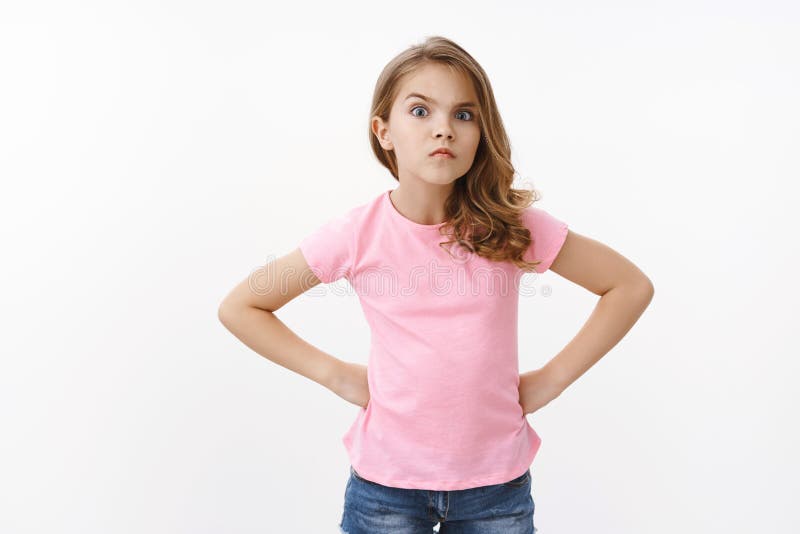 Serious-looking strict and angry little arrogant girl, blond child, stand in bossy offended pose, hold hands waist demand answers, staring seriously camera squint and frowning, scolding friend.