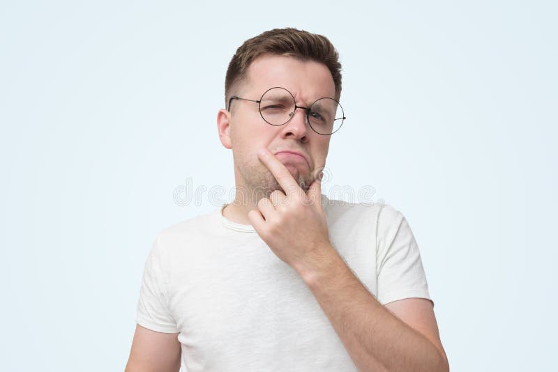 serious-male-student-white-t-shirt-wears-optical-round-glasses-looks-seriously-has-strict-puzzled-look-tries-to-decide-what-do-163298523.jpg