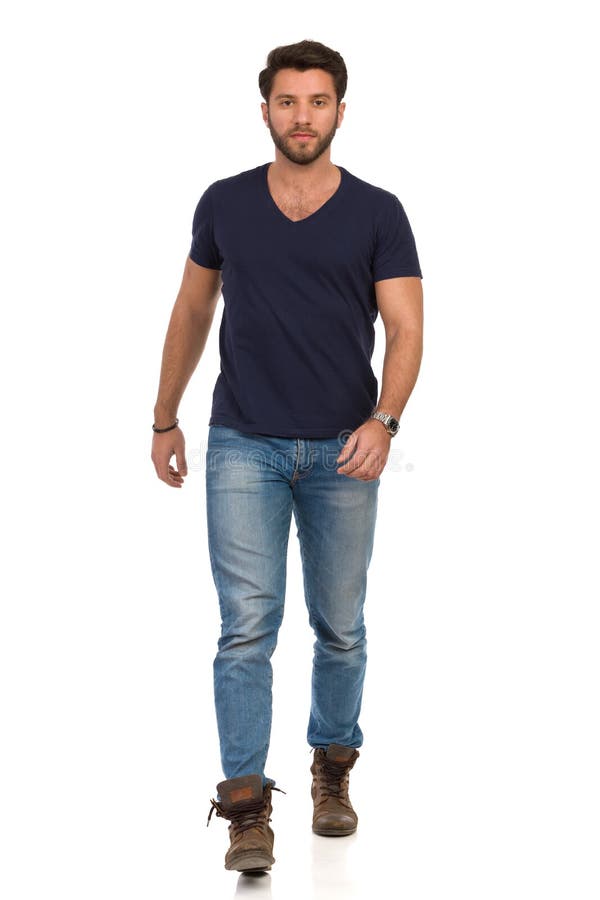 Serious Man In Blue T-shirt, Jeans And Boots Is Walking Towards Camera