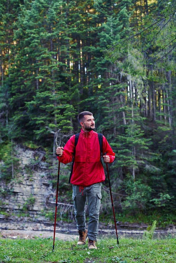 Serious man with poles hiking in mountains