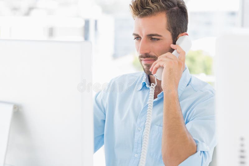 Serious man using phone and computer in office