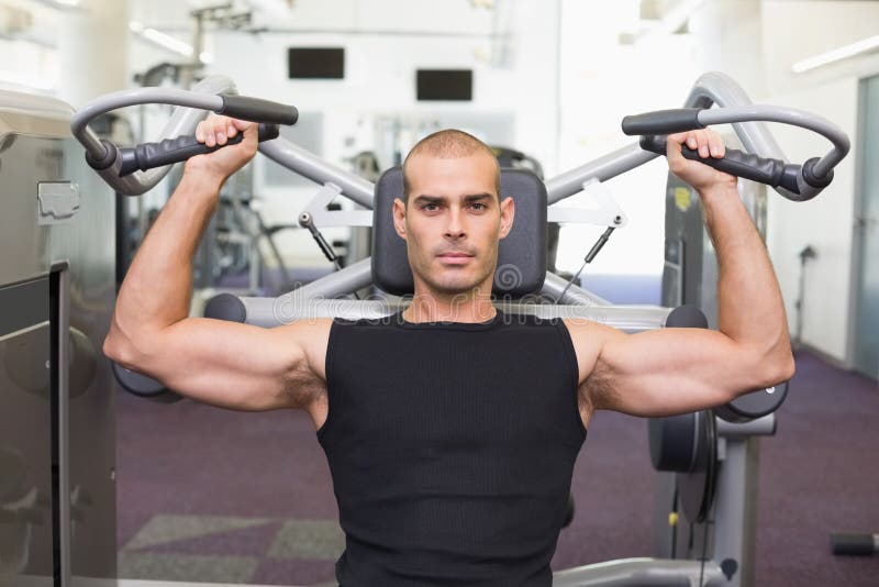 Serious man working on fitness machine at gym