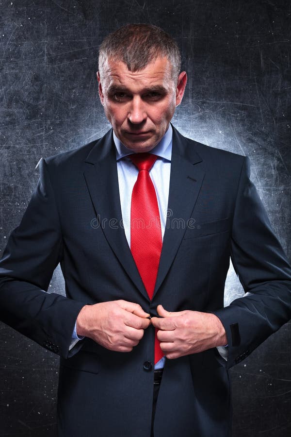 Dramatic picture of a serious old business man unbuttoning his suit