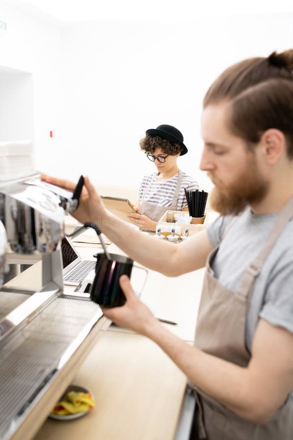 Waitress writing down orders while barista making coffee royalty free stock images