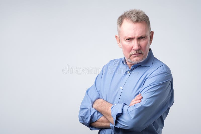 Serious senior man in blue shirt with folded arms stock photo Serious senior man in blue shirt with folded arms stock photo